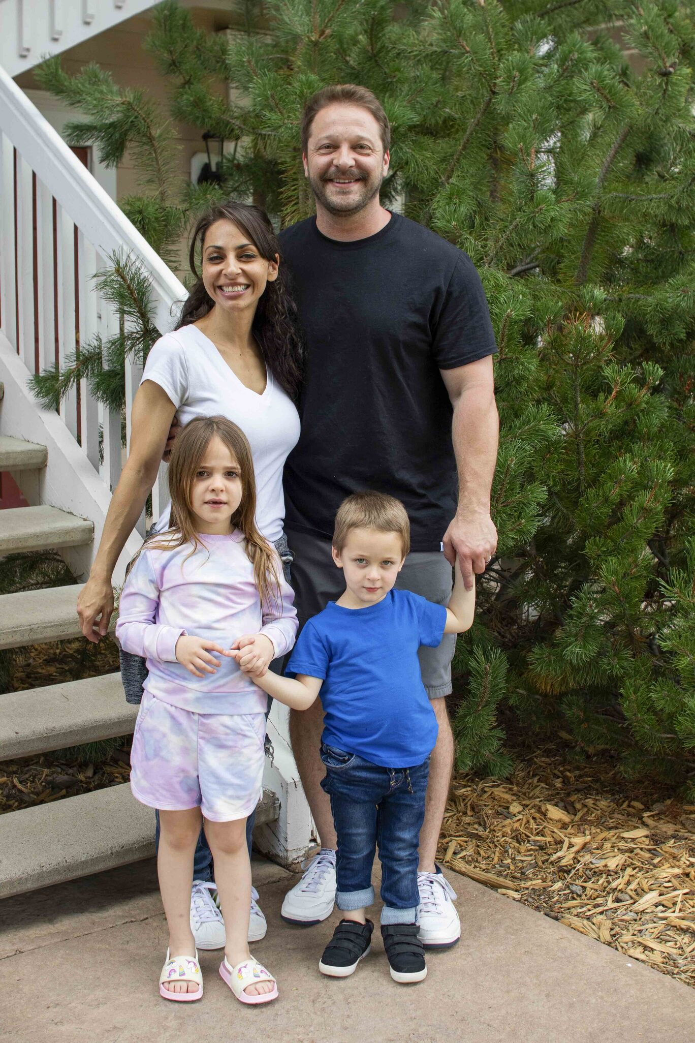 Lea and Gabriel smiling and posing for the camera while standing outdoors with their daughter Isa and son Isaiah.