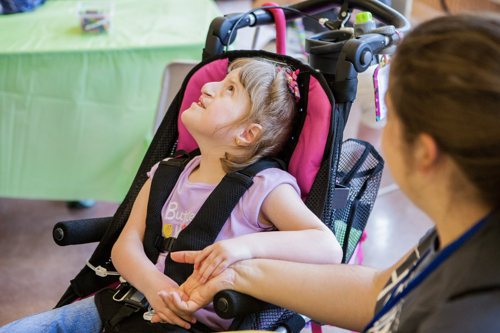 A girl on her stroller holding hands with a woman during the Family Retreat