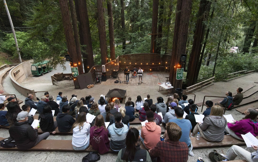 Campers sit in an amphitheater in the woods