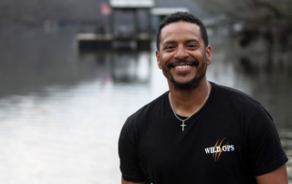JB Basaldua smiling at the camera with a river in the background.