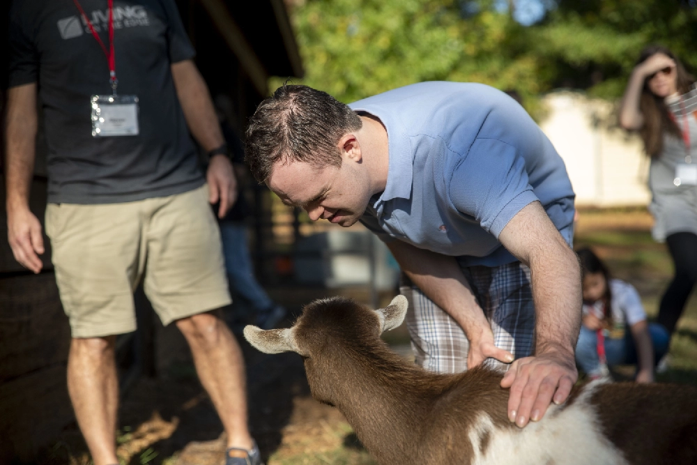 A man pets a brown and white goat at Family Retreat