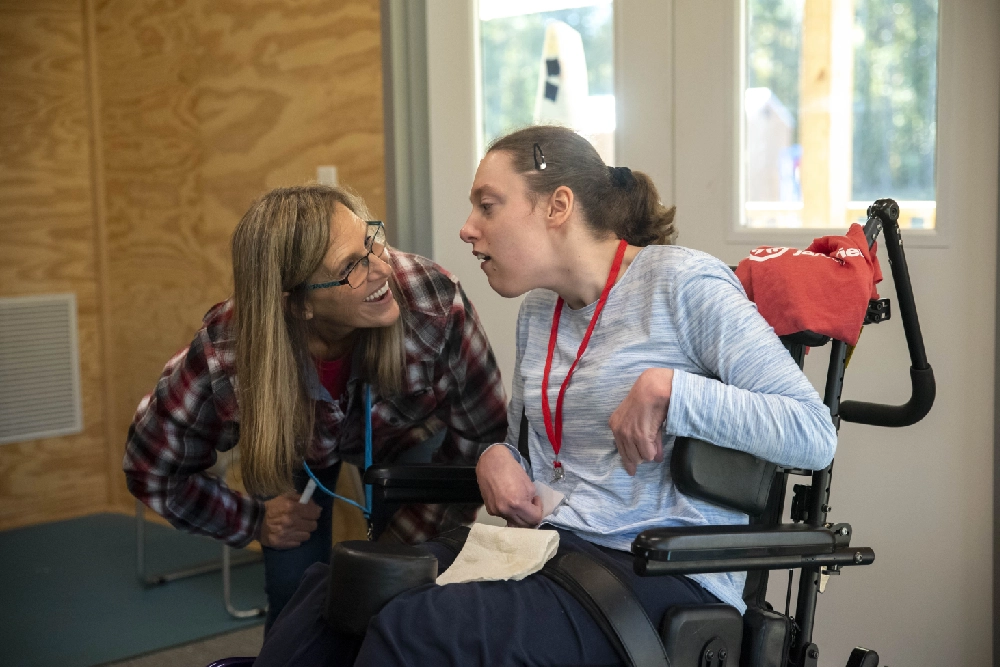 A volunteer and camper in a wheelchair pose for a photo