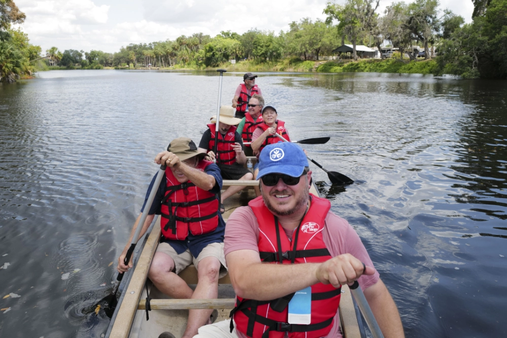 Campers in a canoe row along the river at Family Retreat
