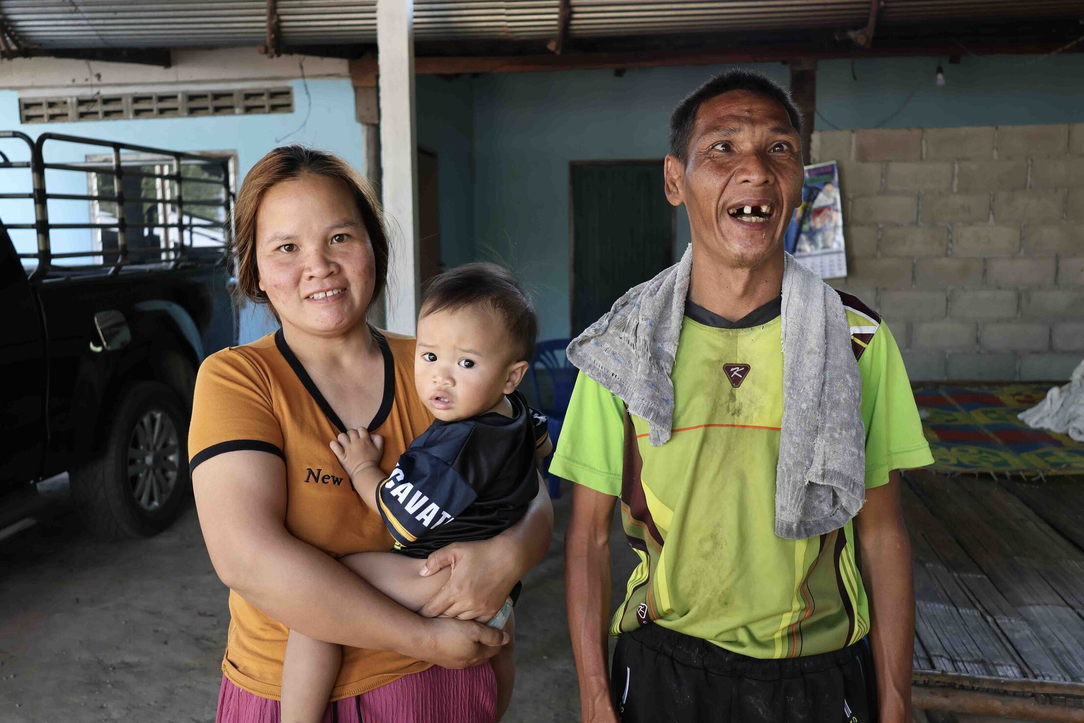 Janga stands next to her sister, who is carrying her young son. All three are smiling brightly, looking happy and excited.
