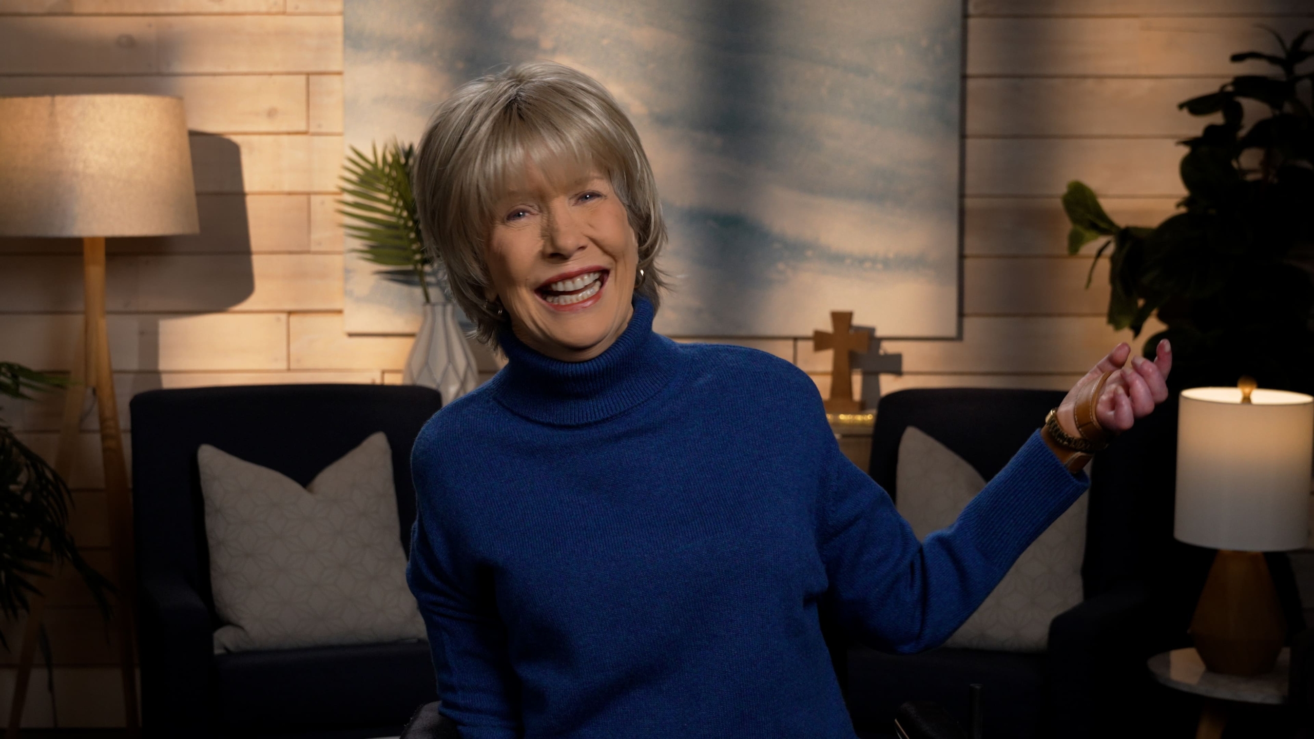 Joni Eareckson Tada smiling, wearing a long-sleeve turtle neck in a cozy living room.