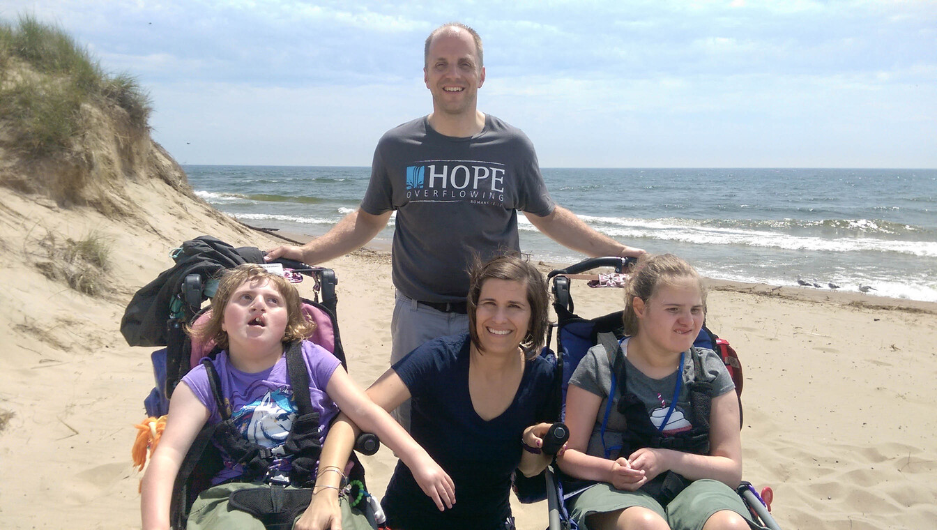 Paul and Kathy smiling with their daughters, Katelyn and Madelyn, by the ocean.