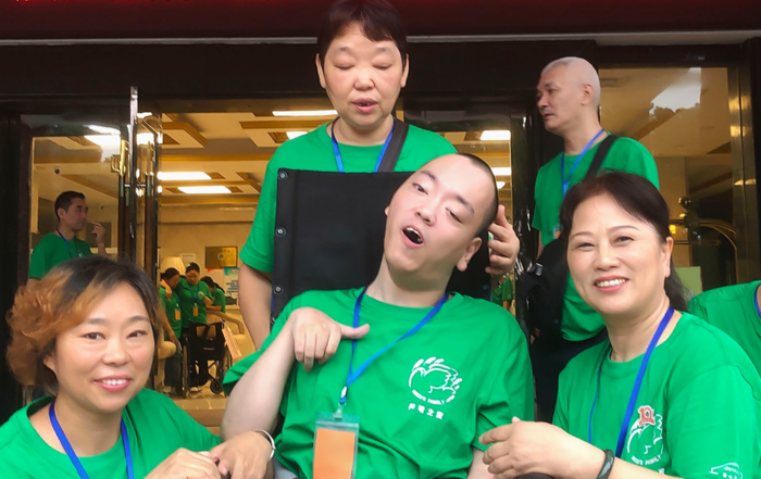 Lu Tong in his new wheelchair, a gift from Joni and Friends, smiling with the three volunteer women at the International Family Retreat.