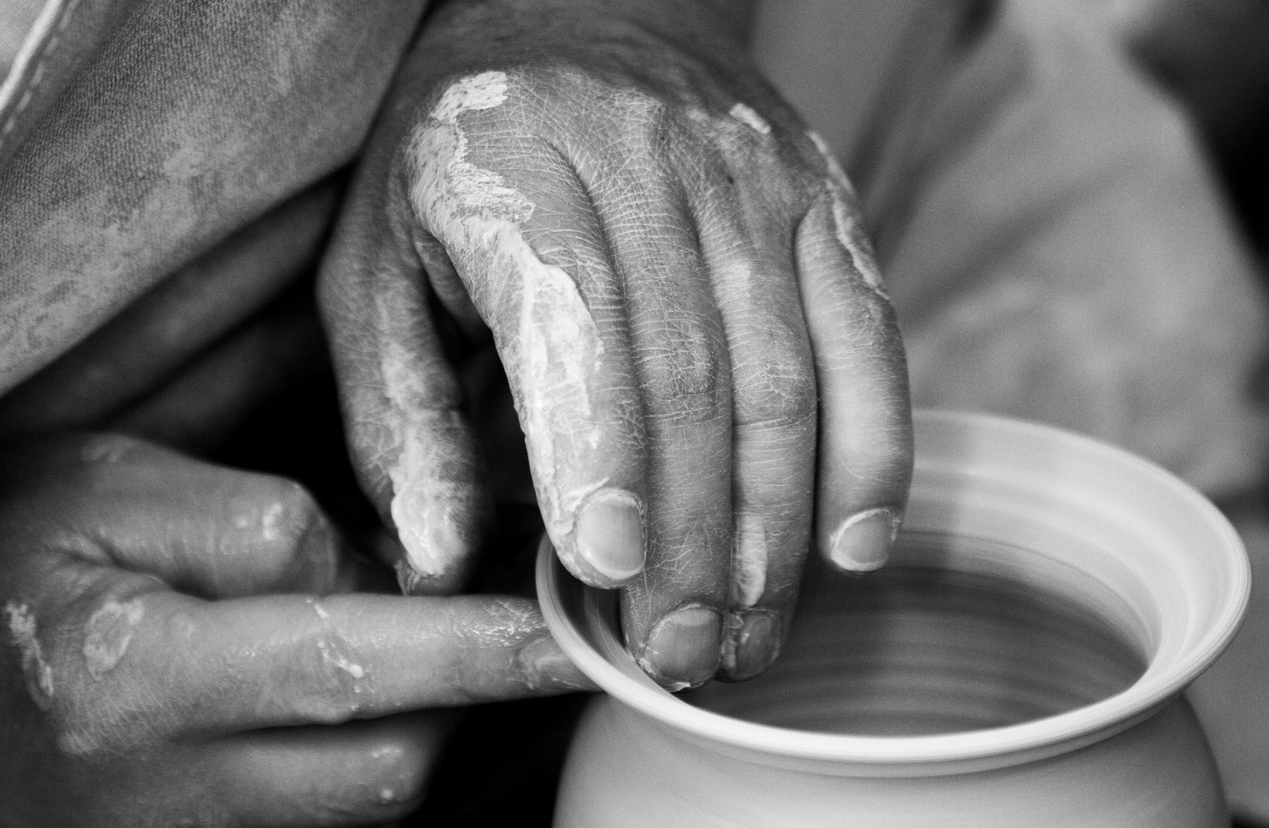A close-up photo of a hand shaping clay on a pottery wheel.
