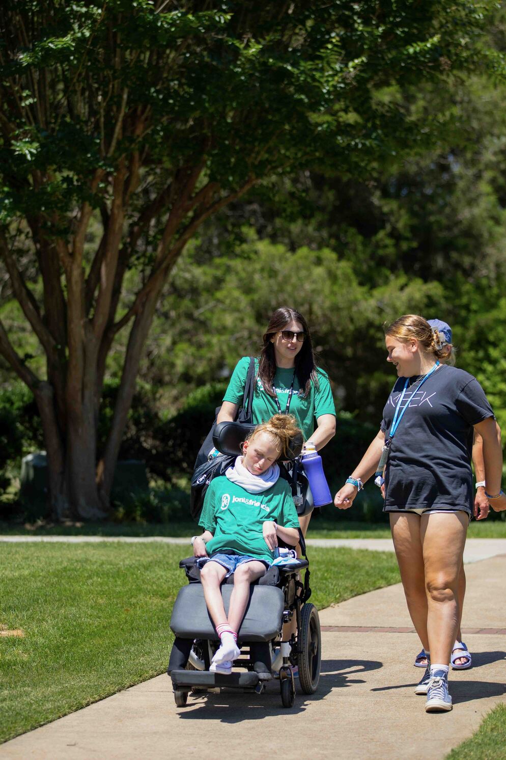 Avonlea being pushed by a volunteer in her wheelchair, with her sister next to her.