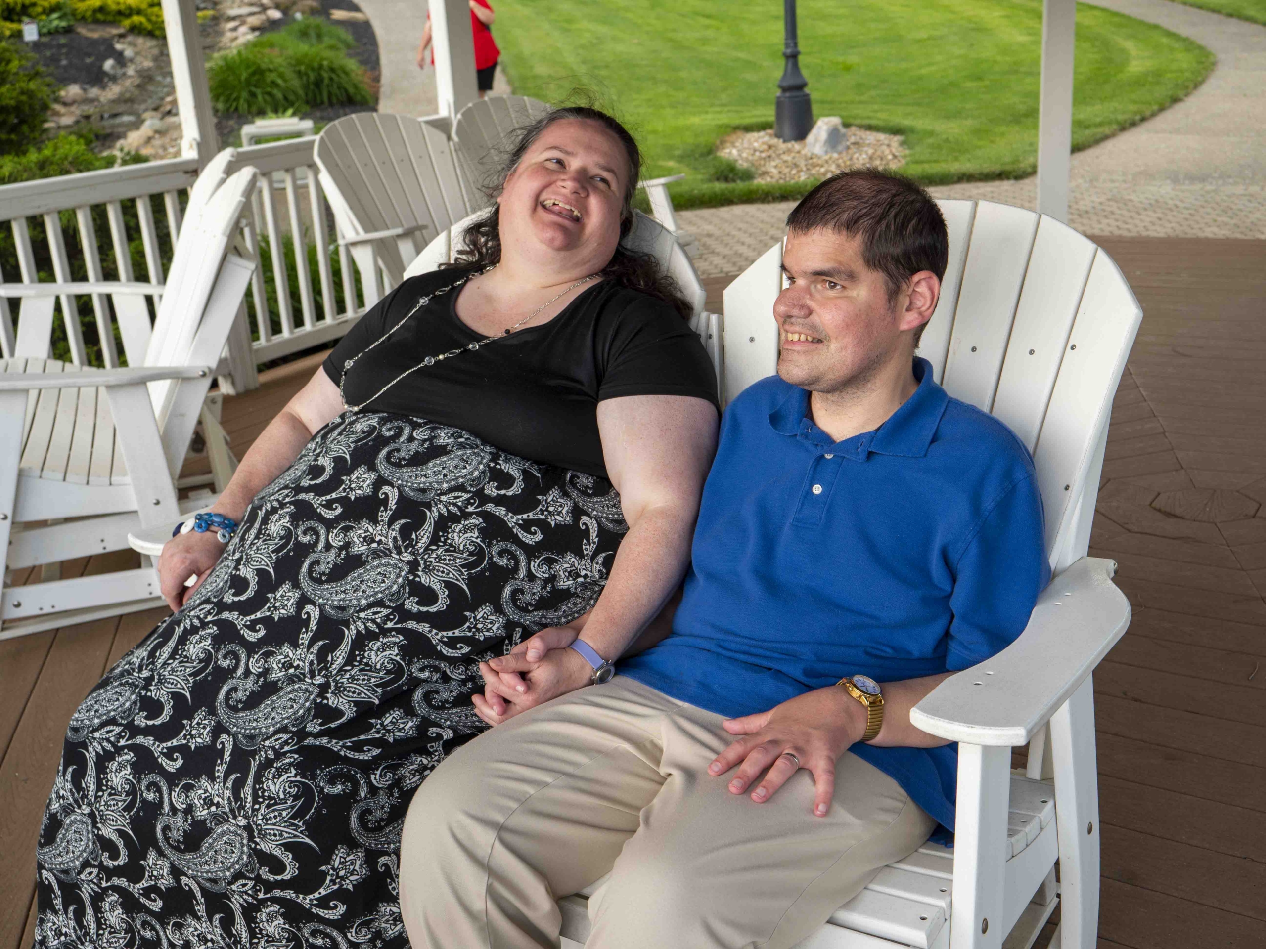 Nick and Rachel sitting on a chair, holding hands and smiling, appearing to enjoy their time together.
