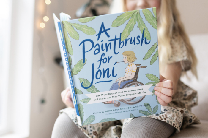 A child holds the book A Paintbrush for Joni