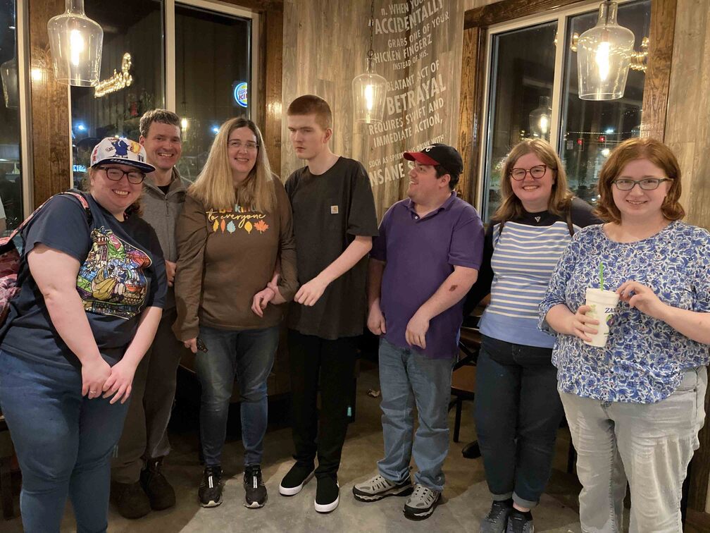 Jennifer and Michael Clayton with their five children, all smiling for the camera inside a restaurant.