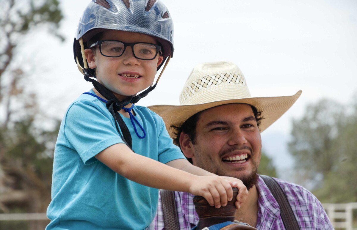 One of Tara's sons riding a horse with a volunteer next to him.