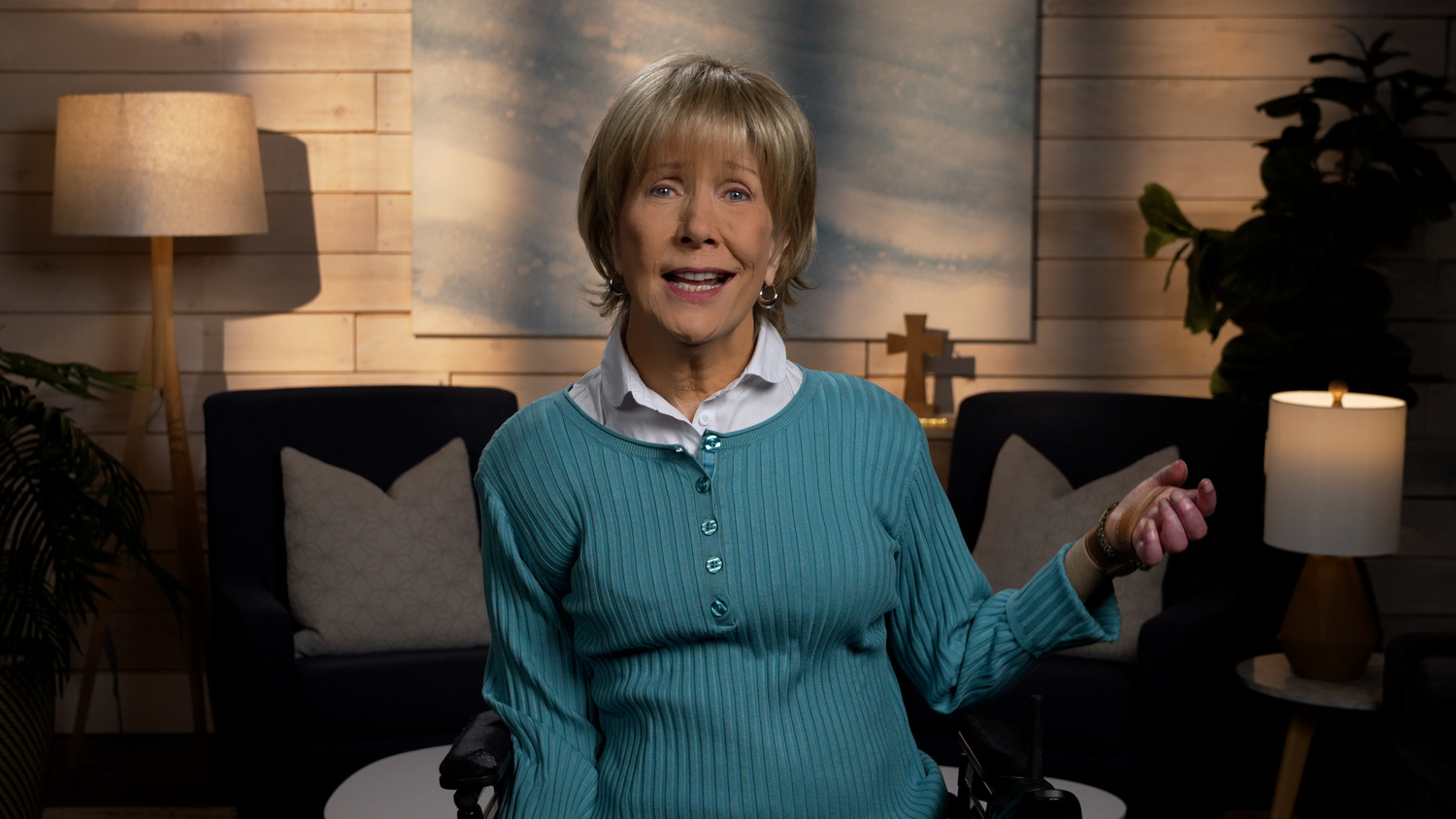 Joni Eareckson Tada smiling, wearing a long-sleeve in a cozy living room.