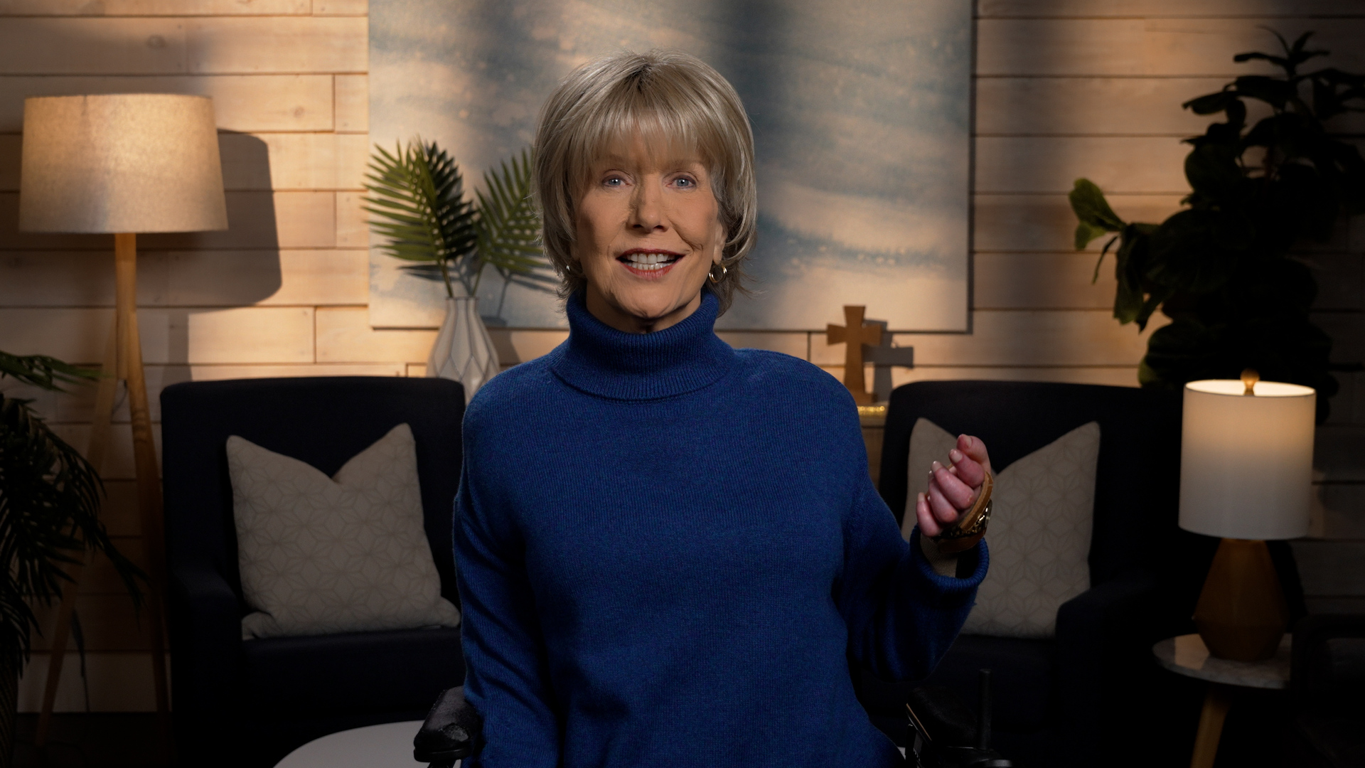 Joni Eareckson Tada smiling, wearing a long-sleeve turtle neck in a cozy living room.
