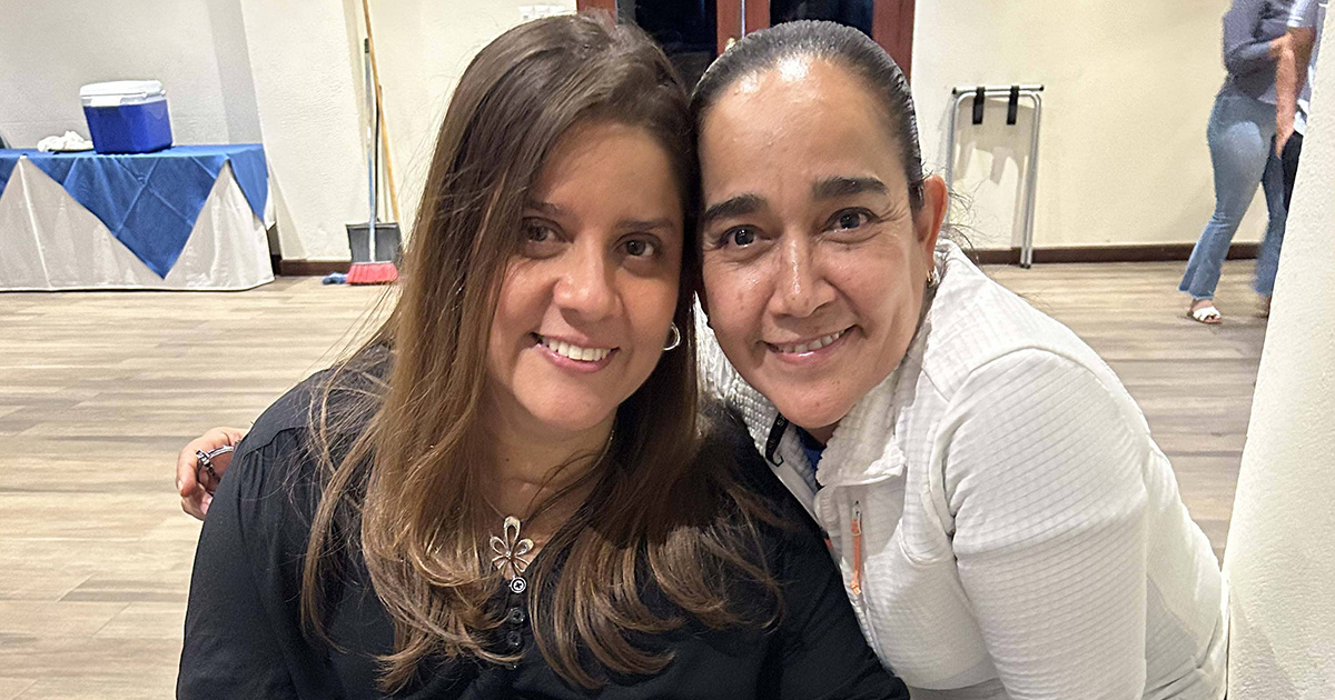 Imelda Cuevas standing next to a woman in a wheelchair, both smiling and posing for the camera.