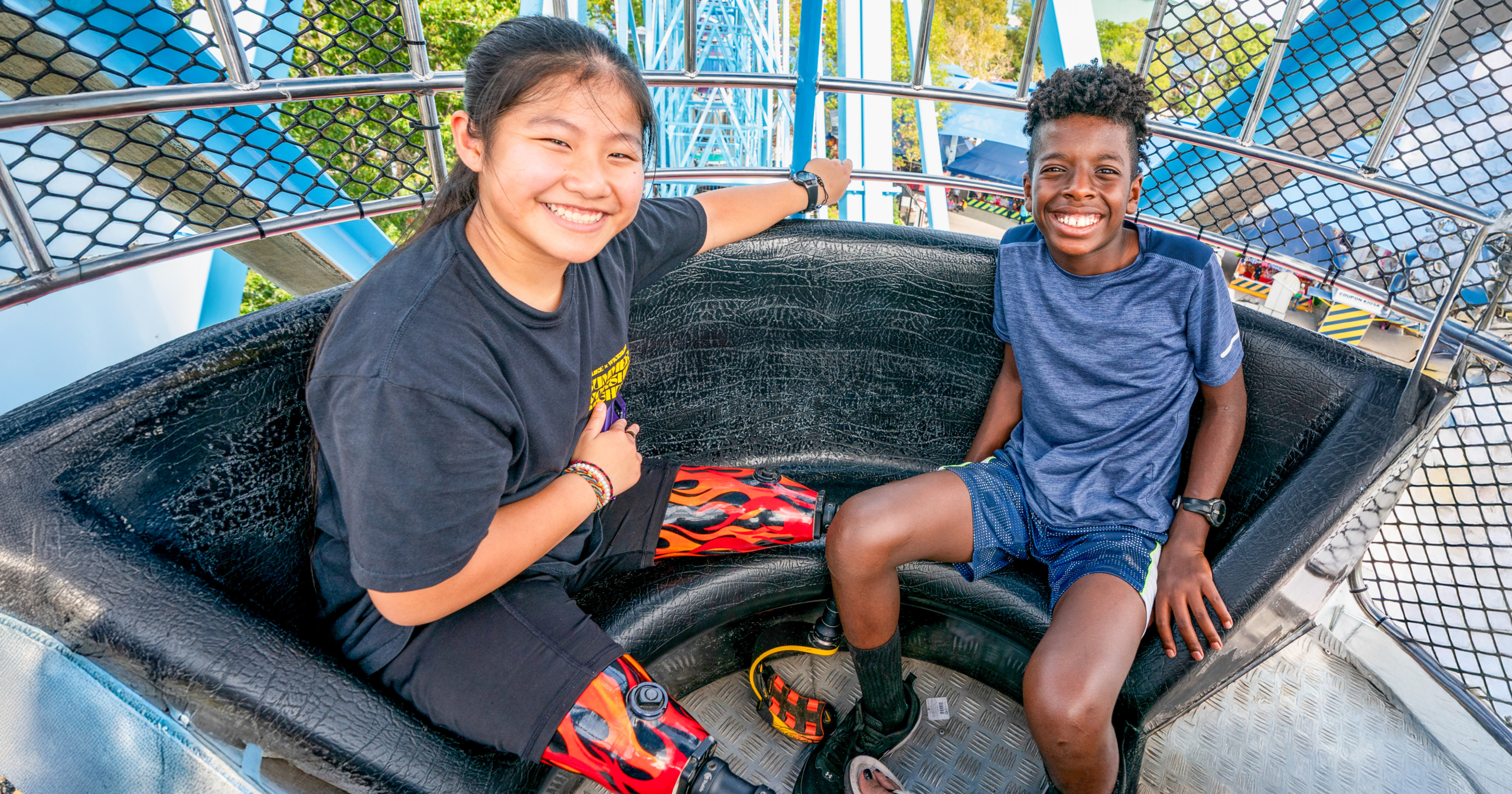 WEB_23_TX_Sensory_State_Fair_0083_1200x630_ Two children have huge smiles while having fun on a ride at the fair.