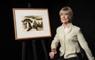 Joni sitting on the left in her wheelchair next to her painting of a horse in motion.