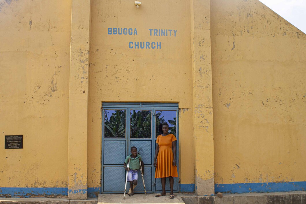 Angello stands with his crutches and his mom Mary in front of Bugga Trinity Church.