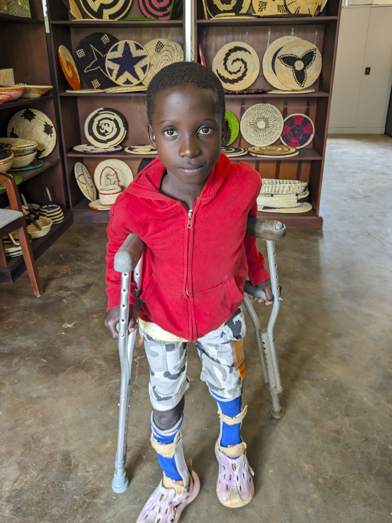 Angello stands with his crutches and leg braces.