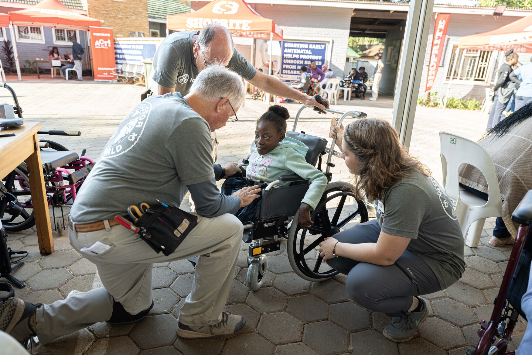Chichi sits in her new wheelchair as a seating therapist adjusts it to fit her.