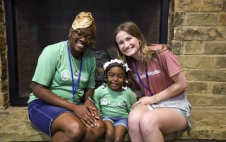 Victoria, Taliyah, and a volunteer at Joni and Friends sitting together, smiling and posing for the camera.