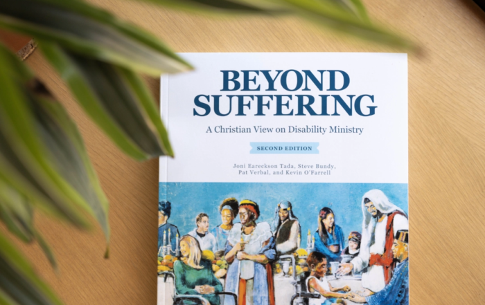 Book cover of "Beyond Suffering, Second Edition," featuring an illustration of the Luke 14 banquet, with Jesus standing at a table surrounded by people with disabilities.