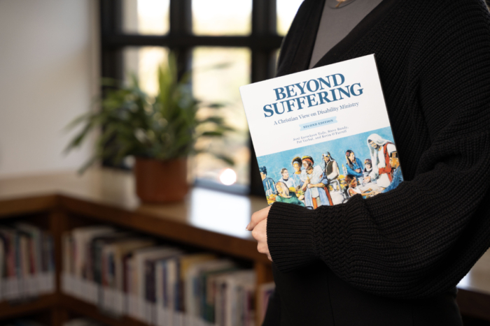 A student holding the Beyond Suffering second edition book in a library