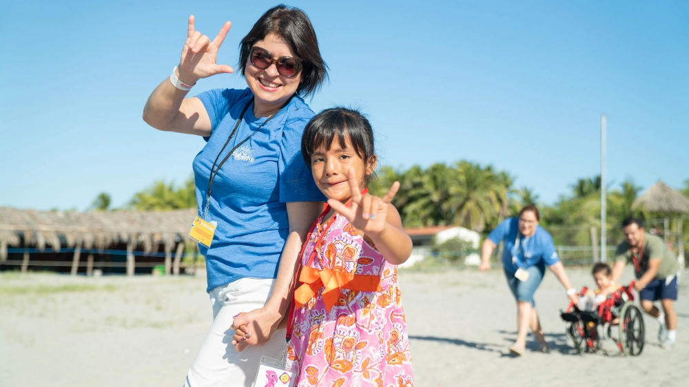 Campers signing "I love you" on a beach at an International Family Retreat
