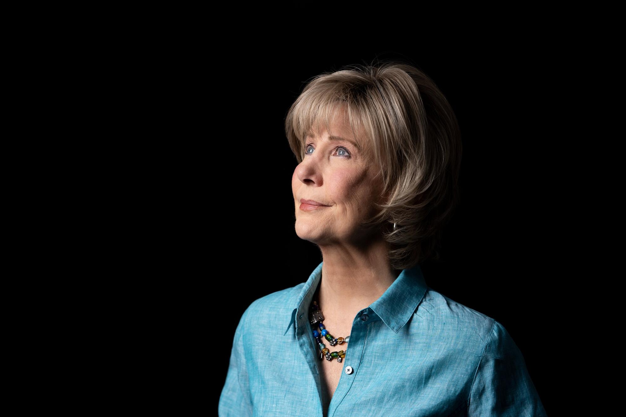 Side view of Joni Eareckson Tada looking upward against a pitch-black background.