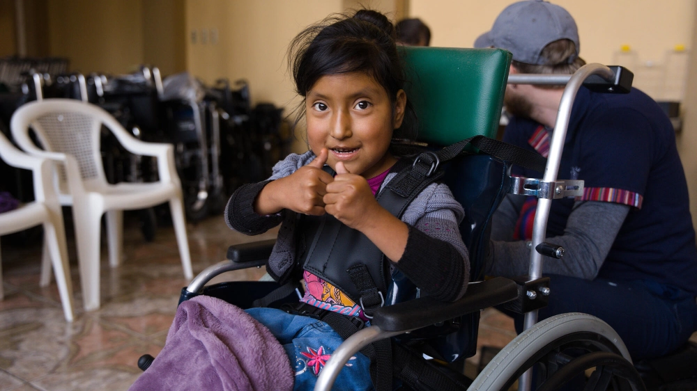 A girl give a thumbs up in her new wheelchair at a Wheels for the World® outreach