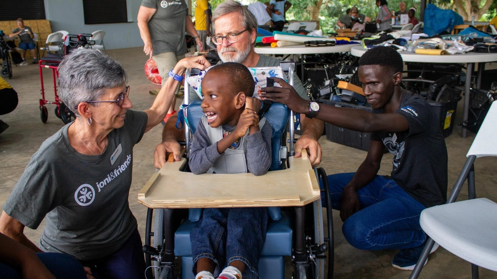 A child smiling in his new wheelchair at a Wheels for the World® outreach