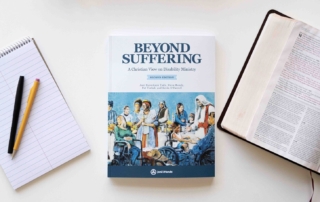 Book cover of Beyond Suffering: A Christian View on Disability Ministry, Second Edition, featuring the Luke 14 Banquet Mural where Jesus welcomes people with diverse disabilities. An open Bible is on the right, open to Luke 14, and a notepad with a pencil and pen is on the left.