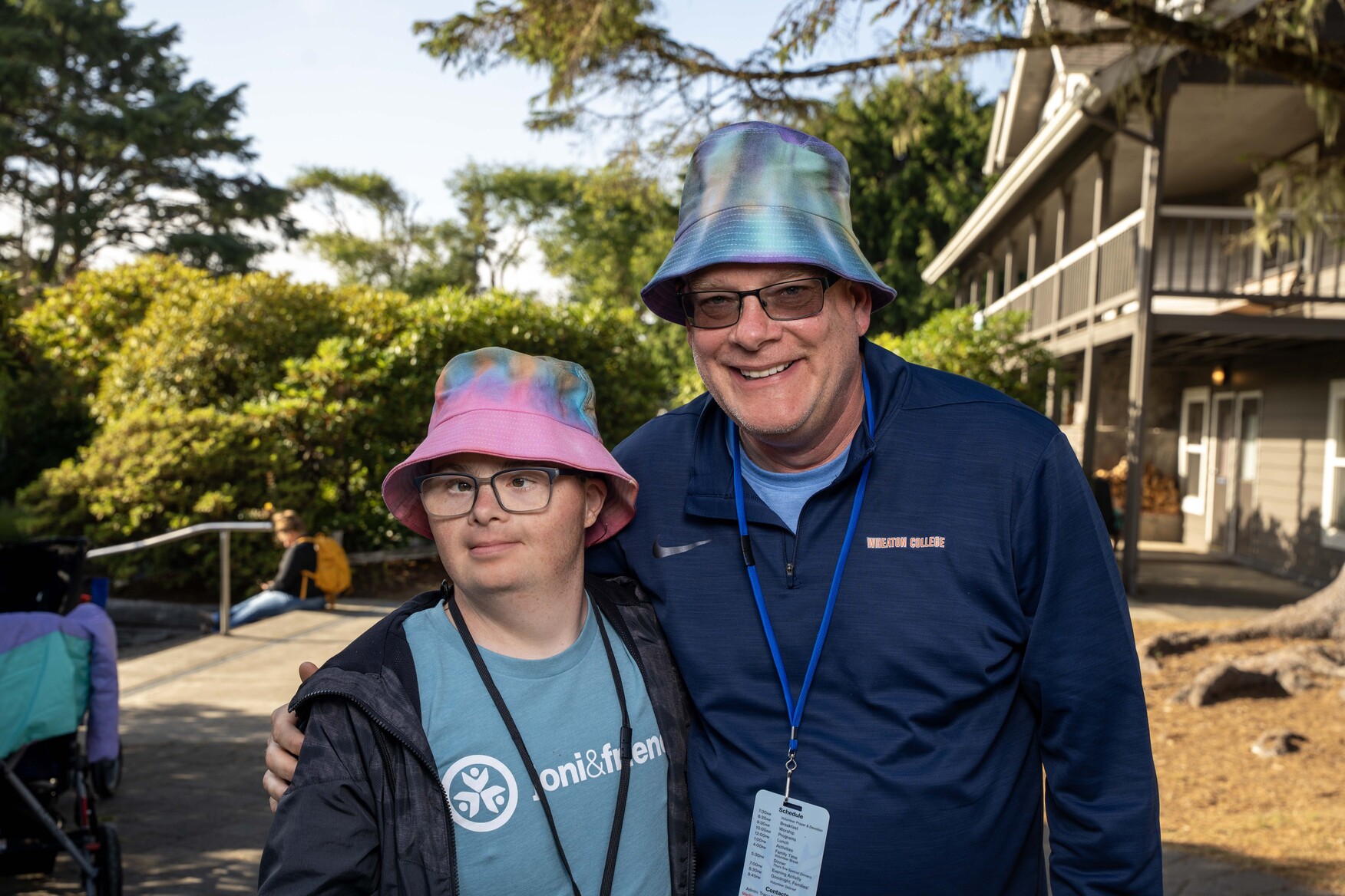 Paul, a man with Down syndrome, and Shawn wearing colorful bucket hats, smiling at the camera.