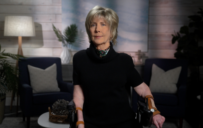 Joni Eareckson Tada looking intently at the camera. The background features a softly blurred living room setup, adding a cozy atmosphere to the image.