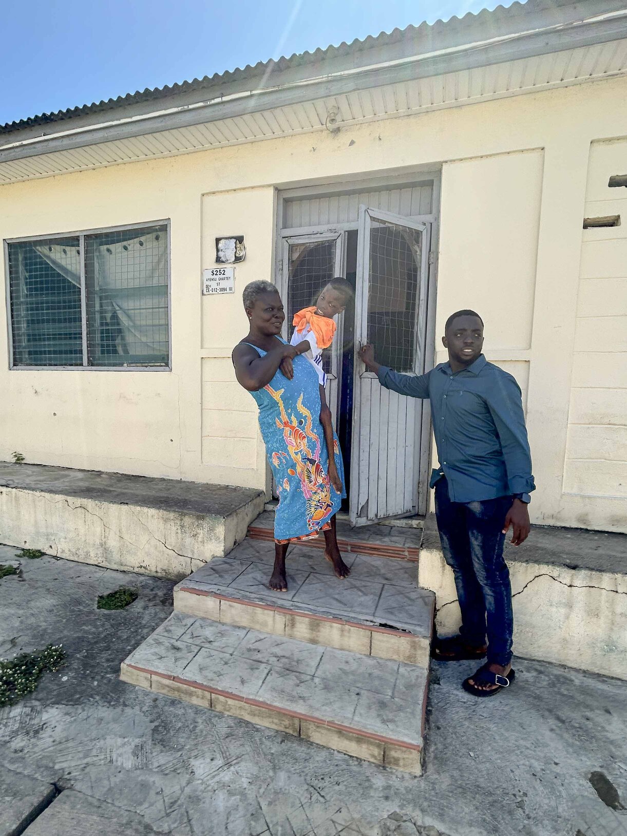 Julianne carrying Kofi as a man opens the door for them.