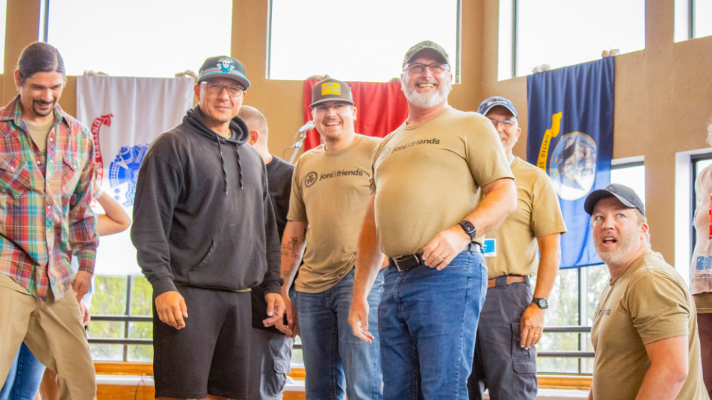 Veterans pose for a photo with military flags behind them