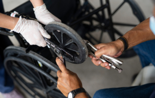 Close-up of hands fixing the wheel of a wheelchair with a wrench.
