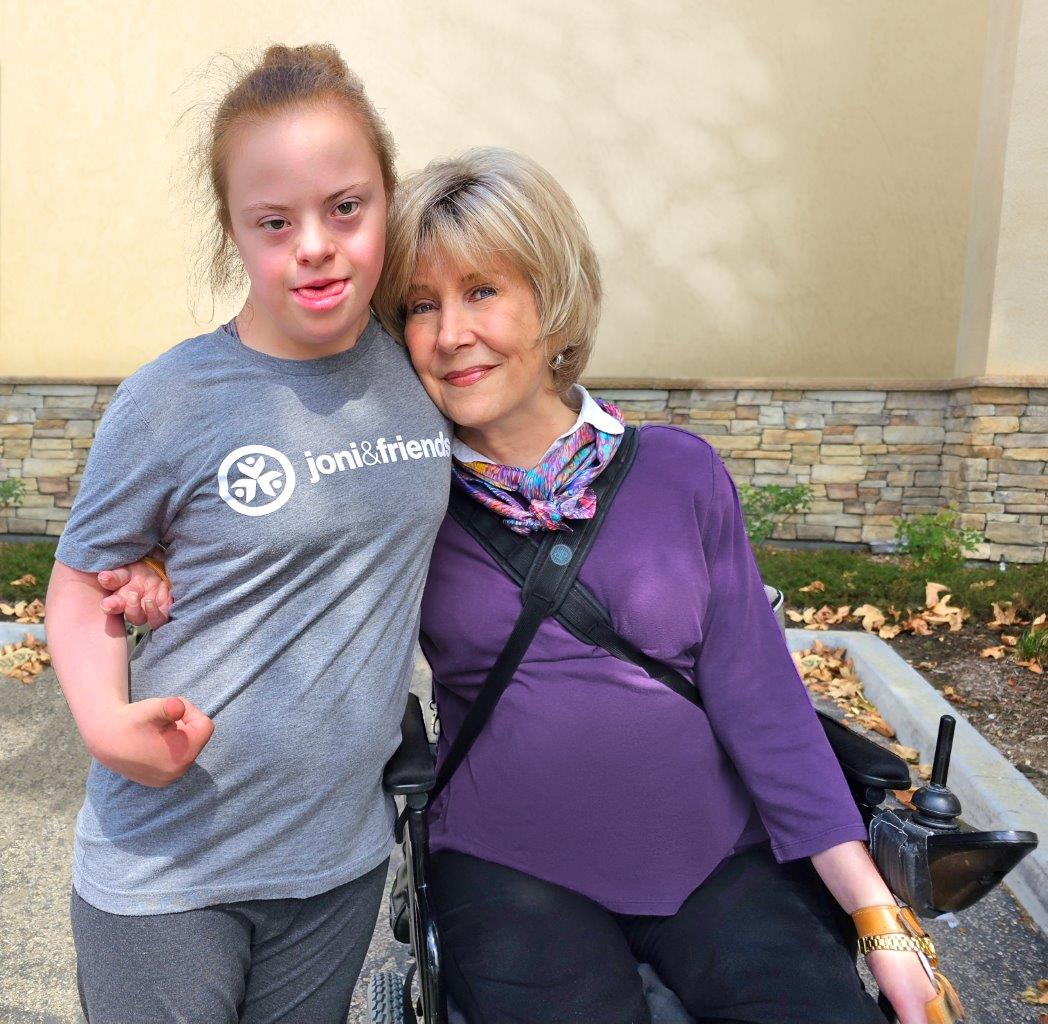 Sarah, wearing a shirt with the Joni and Friends logo, sitting next to Joni Eareckson Tada.