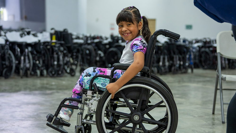 A girl smiles as she poses for photo in her new wheelchair