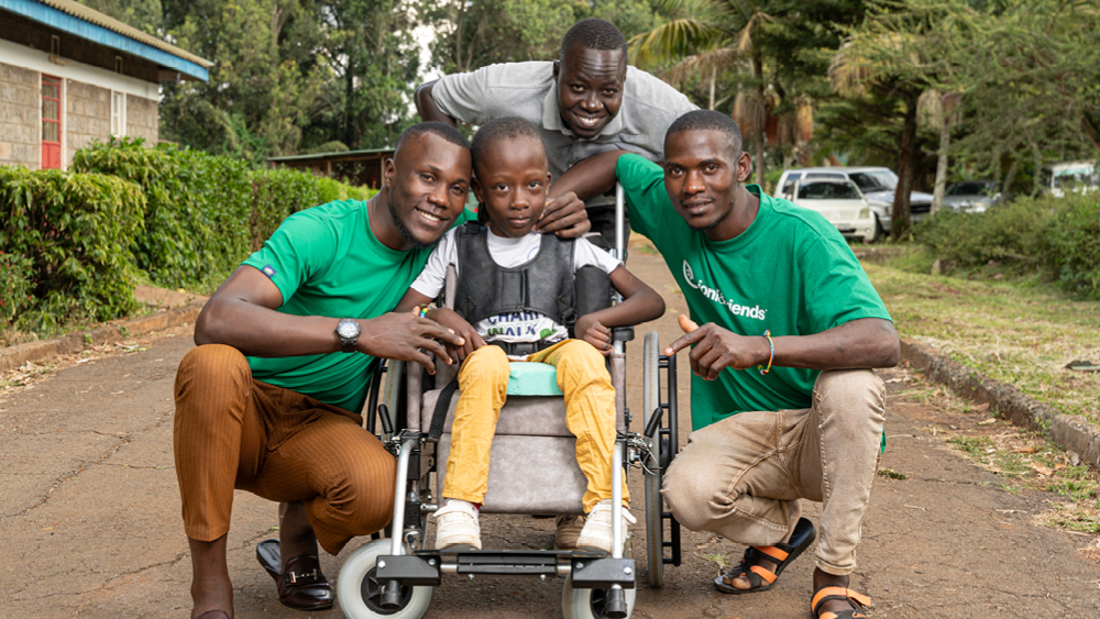 A boy in his new wheelchair surrounded by family and volunteers