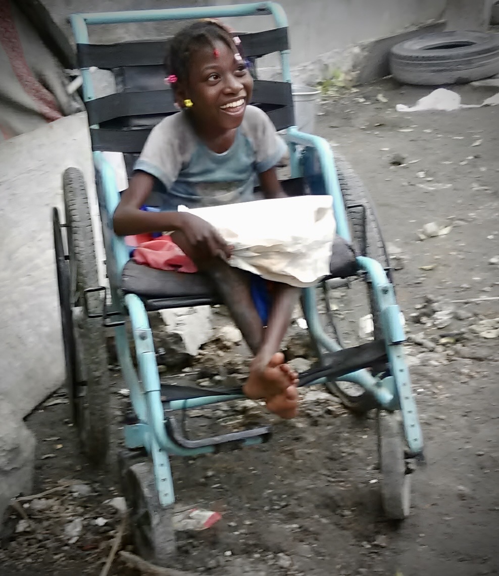 Kesna in her wheelchair smiling brightly for the camera.