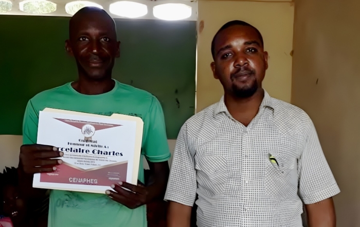 Alfreno next to a Motorbike taxi driver. Both are smiling for the camera.