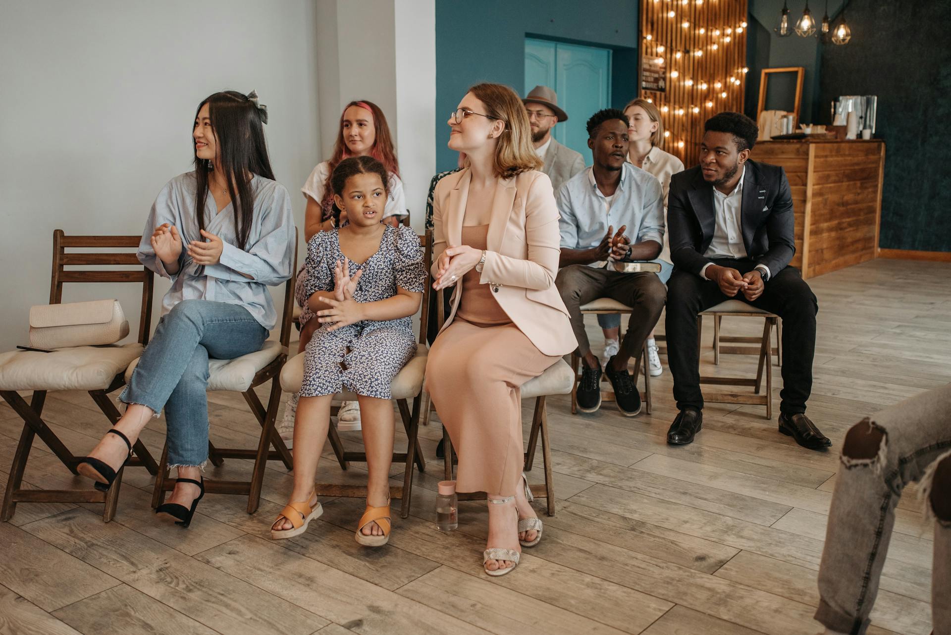 A girl glancing to the side during a church service, while adults in the background are clapping.