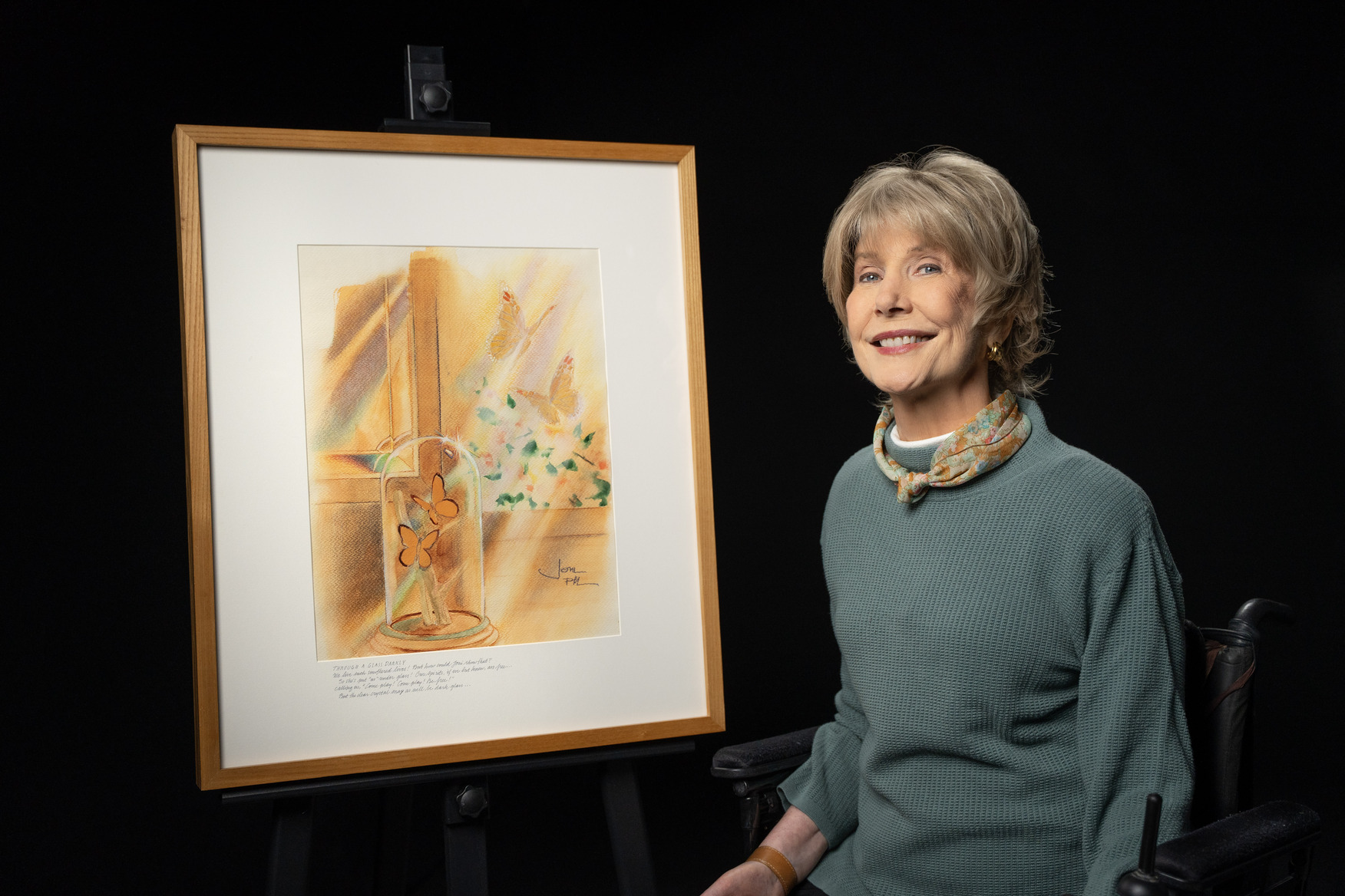 Joni Eareckson Tada sits beside her painting Through a Glass Darkly, which depicts butterflies inside a glass dome and others flying outside a window.