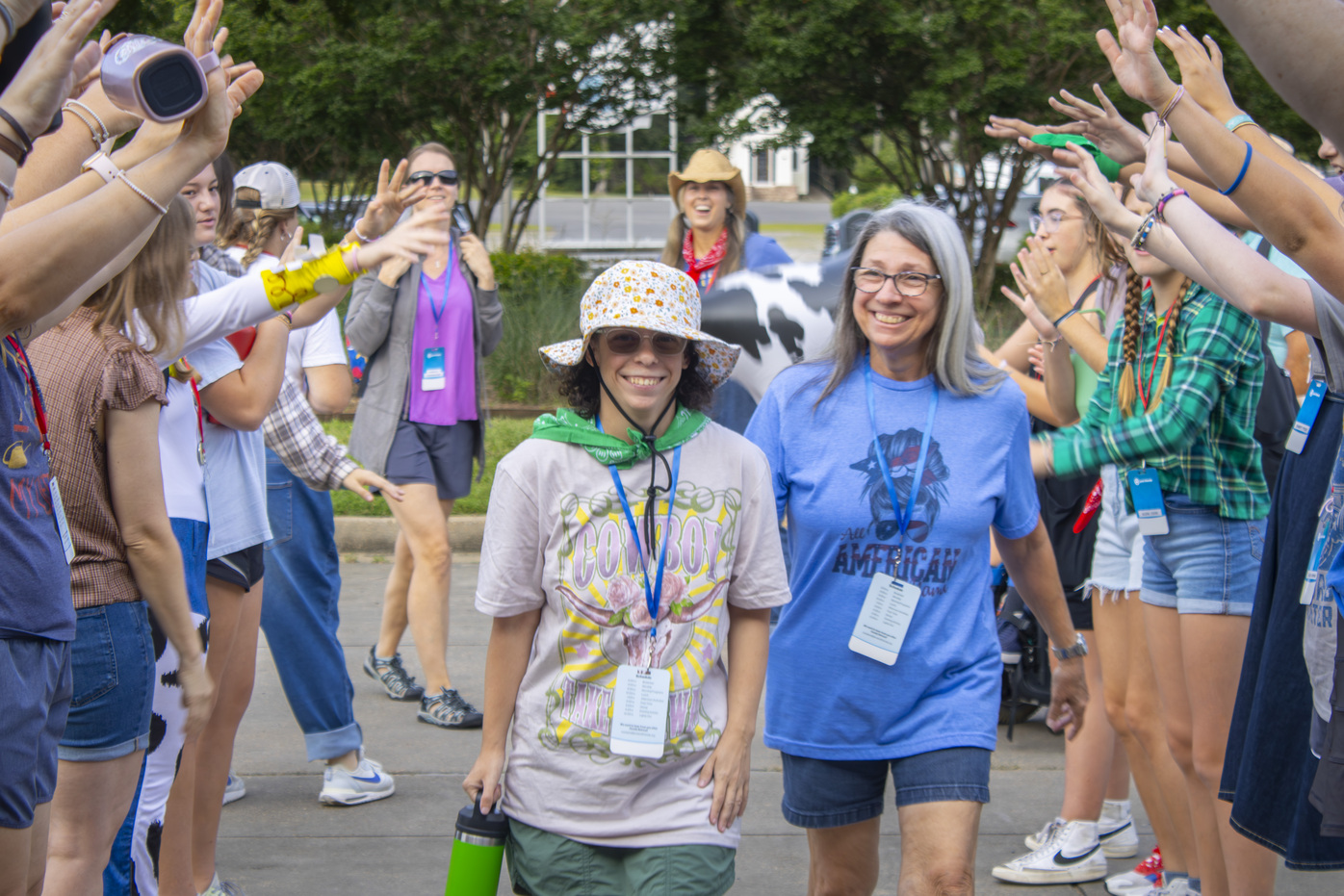 Bailey and Lorna walk into the Family Retreat, smiling as people on both sides welcome them.