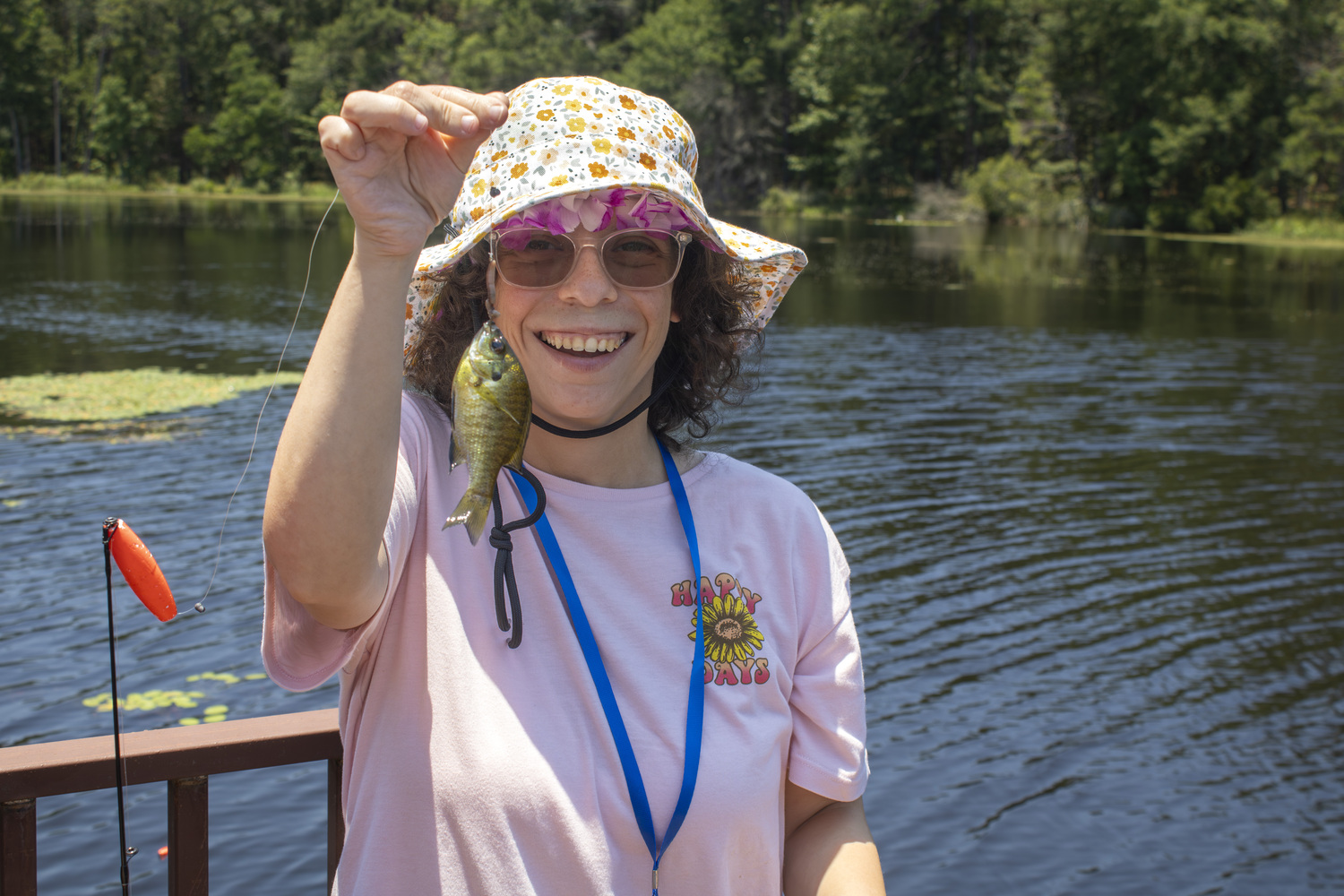 Bailey smiles excitedly as she holds a fishing net with a fish caught on the bait.