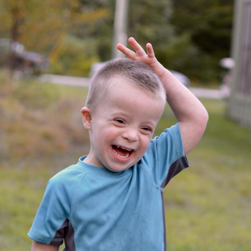 Jacob, a young boy with Down Syndrome, smiling brightly.