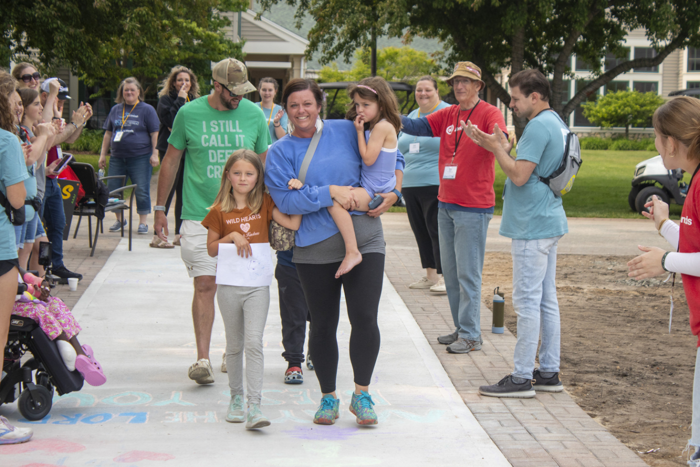 Austin and Melissa with their three children arriving at Family Retreat, with volunteers on either side welcoming and clapping for them.