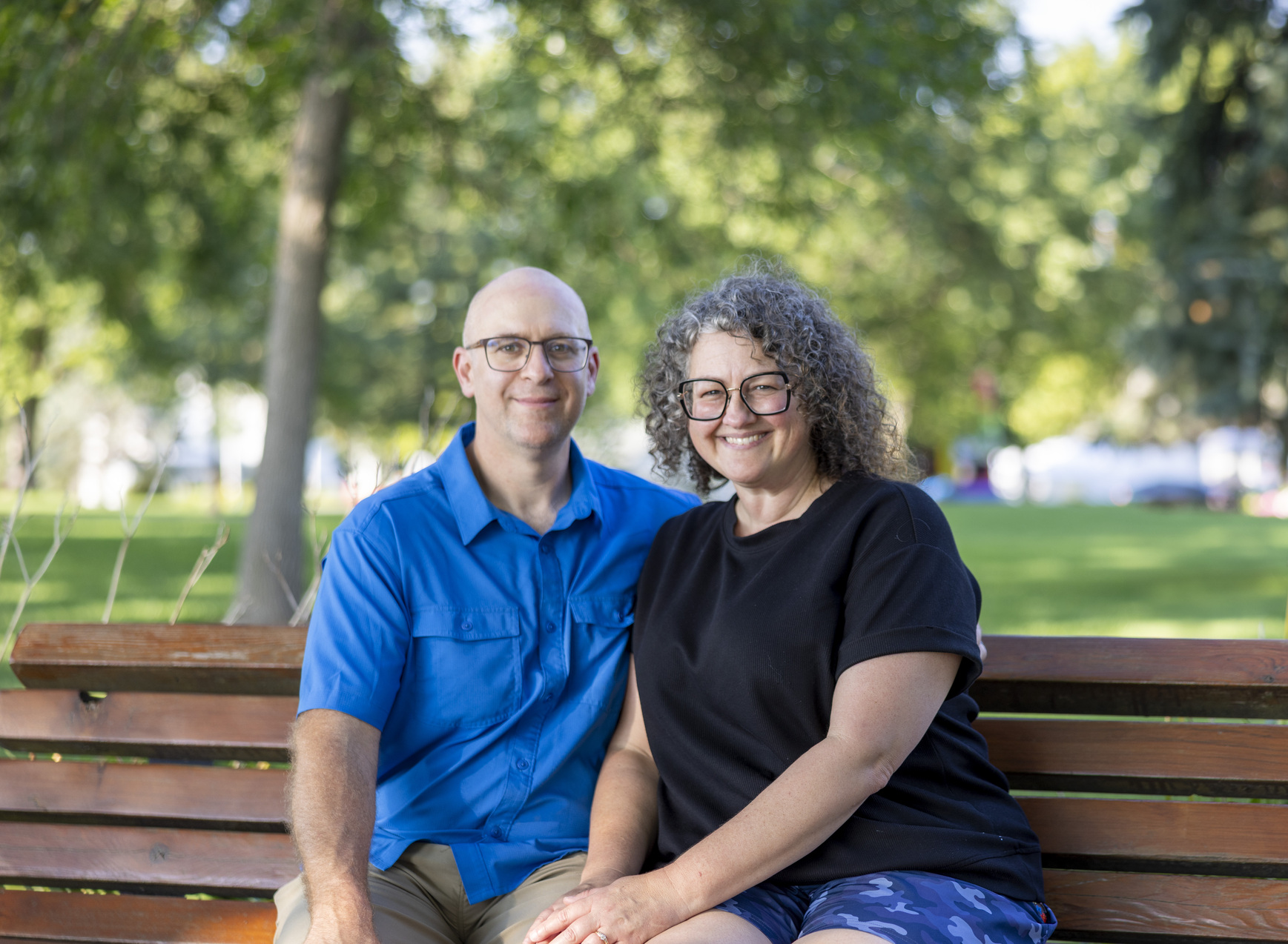 Matt and Julia sitting on a bench while smiling for the camera.